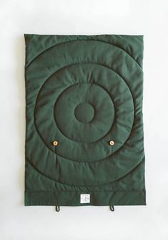 a green blanket with gold buttons on the bottom and an inner circle in the middle