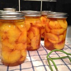 four jars filled with pickles sitting on top of a table