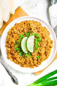 a white plate topped with rice covered in beans and garnished with a lime