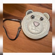 a small white purse with a bear face on the front and side, sitting on a wooden surface