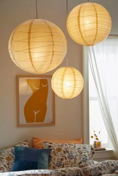 three paper lanterns hanging from the ceiling above a couch in a living room with pillows on it