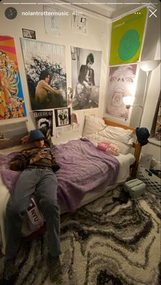 a person laying on top of a bed in a room filled with pictures and posters