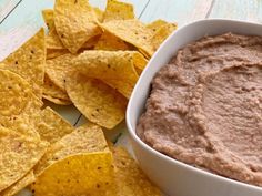 a white bowl filled with brown dip surrounded by tortilla chips