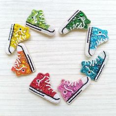 six pairs of colorful converse shoes with sequins on the bottom are arranged in a circle