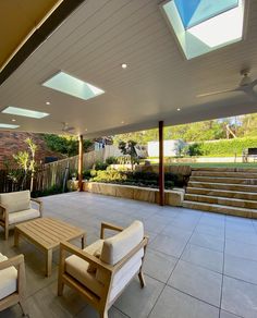 an outdoor patio with seating and stairs leading up to the roof area that has skylights above it