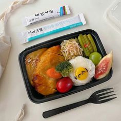 a plastic container filled with different types of food and utensils on top of a table