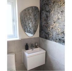 a white sink sitting under a mirror in a bathroom next to a toilet and window