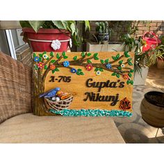 a wooden sign sitting on top of a chair next to a potted plant with flowers