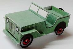 a green toy truck with red wheels on a white surface