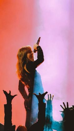 a woman holding a bottle while standing on top of a stage