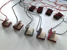 several pieces of paper with wires attached to them sitting on a white table next to books