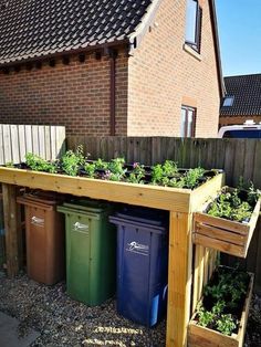 an outdoor garden area with plants growing out of the planter boxes and trash cans