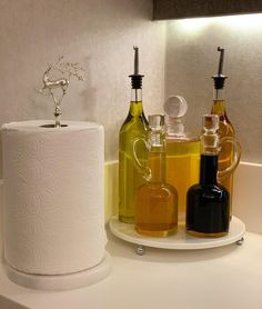 a bathroom counter with toilet paper, oil and soap dispensers