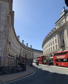 two red double decker buses driving down the street