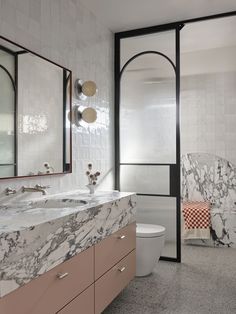 a bathroom with marble counter tops and pink cabinets