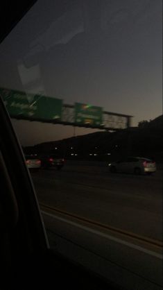 cars driving on the highway at night with an overpass in the backgrouund