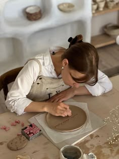 a woman in an apron working on a clay sculpture with her hands over the top