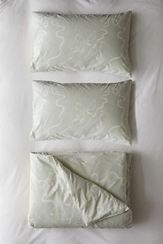 three pillows and two pillow cases on a bed