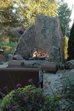 an outdoor fire pit surrounded by rocks and flowers