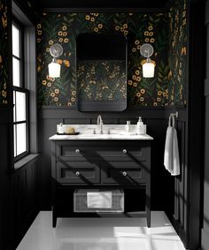 a black and white bathroom with floral wallpaper on the walls, two sinks and a large mirror