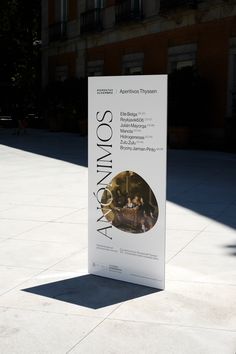 a white sign sitting on top of a sidewalk