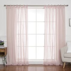 a living room with a couch, chair and window covered in pink sheer curtain panels