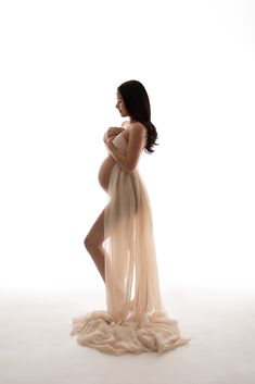 a pregnant woman in a dress poses for the camera with her hands on her belly