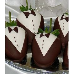 four chocolate covered strawberries in the shape of groom's suits on a silver platter