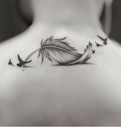 the back of a woman's neck with birds flying around and a feather on it