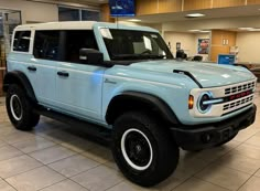 a light blue truck is parked in a showroom