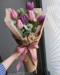 a bouquet of tulips wrapped in brown paper and tied with a pink ribbon