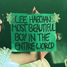 a man holding up a sign that says lee haugh most beautiful boy in the entire world