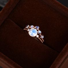 a ring in a velvet box with an opalescent stone on the top and sides