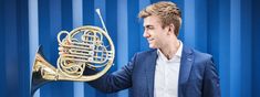 a man in a suit holding a french horn