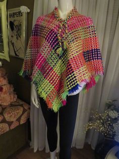 "1970's bright colorful patchwork look crocheted cape/poncho, with fringed edge/ neckline, and braided neckline edge with ties. Poncho has a one way entryover the head! But for a small head fit....22\". The poncho yarn colors are red, orange, white, pink, dark blue, mint, lime, yellow. There is no size or label maker, and this item could be hand made. My size guess is for a petite/small, maybe medium fit, with small head 22\". Great condition. PRICE IS $45.00----SALE FINAL/AS IS/NO RETURNS." One Size Multicolor Crochet Poncho, Multicolor Crochet Poncho One Size, Multicolor One Size Poncho For Festivals, One Size Multicolor Poncho For Festival, Bohemian Crochet Multicolor Poncho, Bohemian Multicolor Crochet Poncho, Multicolor Crochet Bohemian Poncho, Multicolor One-size Festival Poncho, Multicolor Tassel Poncho For Winter