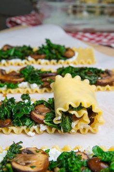 some pasta with spinach, mushrooms and cheese on it sitting on top of a table