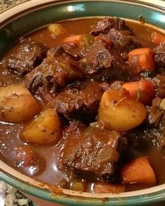 a bowl filled with beef and potatoes on top of a table