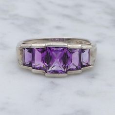 This vintage sterling silver ring features a gorgeous stepped designed head showcasing five stunning emerald cut amethyst gemstones.  Measurements: size 8, head width 9mm, weight 4 grams Condition: great vintage condition with light wear Markings - marked as shown Please look closely at all photos and description and message me with any questions you might have, or to request a video.   Please be aware that because of close-up photography, some items may appear bigger on your screen than they are in real life.  This is why I give full measurements and a hand for comparison on all of my items.   If you do not absolutely love your purchase, please message me to arrange a return and full refund. Close Up Photography, Vintage Sterling Silver Rings, Amethyst Gemstone, Amethyst Ring, Emerald Cut, Rings Statement, Vintage Sterling Silver, A Video, Sterling Silver Ring