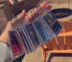 a person holding up several cd's in front of a fire pit and chair