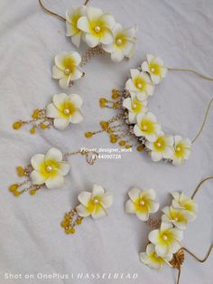 four white and yellow flowers are on a table with brown string attached to the headbands