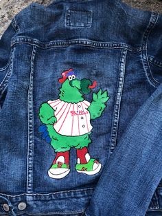 Hand painted Philadelphia Phillies phanatic kids jean jacket. Sealed with protectant finish. Hand wash  Painted on Ralph Lauren polo Jean jacket size M (10-12) If you are interested in this jacket in a different size or color please purchase the jacket under custom order and follow the details as listed to provide all information needed  Message for further details or questions about getting this jacket in other sizes Casual Hand Painted Cotton Outerwear, Casual Cotton Outerwear With Hand Painted Details, Casual Cotton Hand Painted Outerwear, Casual Hand Painted Cotton Denim Jacket, Casual Blue Denim Jacket With Custom Artwork, Casual Cotton Denim Jacket With Custom Artwork, Phillies Phanatic, Hand Painted Jacket, Kids Jeans Jacket