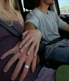 a man and woman sitting in the back seat of a car with their hands wrapped around each other