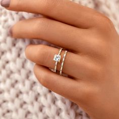 a woman's hand with two rings on top of her finger and one ring in the middle