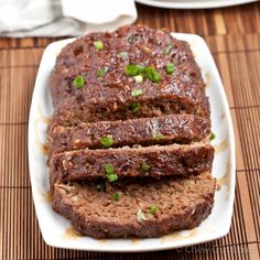 sliced meatloaf on a white plate sitting on a bamboo mat