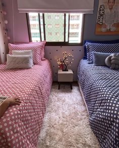 two beds in a room with pink and blue bedding, pillows and rugs