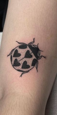 a ladybug tattoo with hearts on the back of its leg, it is black and white