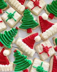 christmas cookies decorated with green and red icing are on a white wooden table top