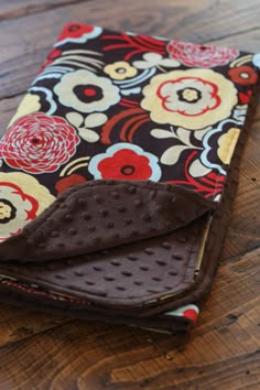 a wallet is sitting on top of a wooden table and has a flower print pattern