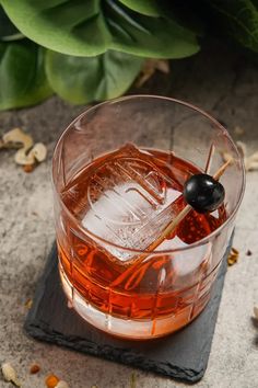 an alcoholic drink in a glass with a black olive on the top