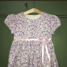 These beautiful brand new handmade mid calf length dresses is a girl's dream with an adorable purple calico set off with a satin pink ribbon and bow. Available in sizes 24 months- 14 years. Bonus! Comes wrapped in brown paper with colored twine! Ideal for Easter, gatherings, special occasions, picnics, parties, and everyday wear. Want a matching bonnet? https://www.etsy.com/listing/1064307888/whitepink-calico-children-pioneer Care:  Wash and dry on your machines' delicate settings with cold water and then put it in your dryer on low or delicate setting, take out as soon as your machine is done and hang it up on a hanger.  No ironing required! This dress was crafted in a smoke free environment. This item is made and created in the USA with pride Purple Short Sleeve Dress For Dress-up Events, Purple Short Sleeve Dress Up Dresses, Lavender Cotton Dress For Garden Party, Lavender Floral Print Cotton Dress, Purple Cotton A-line Dress, Lavender Cotton Dress With Floral Print, Lavender Cotton Dress With Short Sleeves, Toddler Picnic, Calico Dress